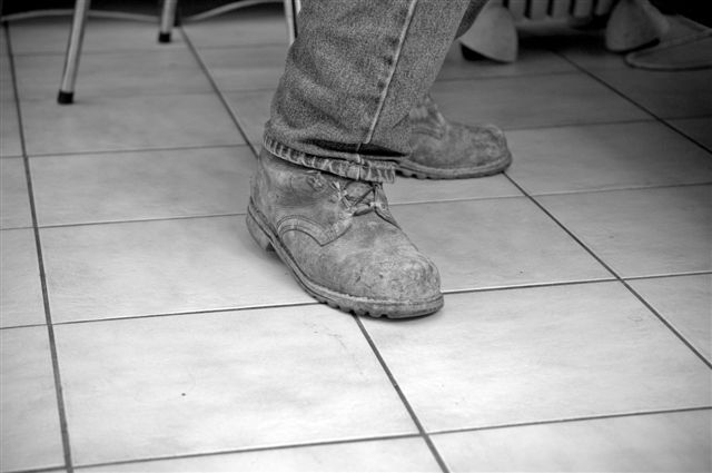Tenue d’un ouvrier touchée par le temps et le travail acharné sur les chantiers. Un jeans et des chaussures usés par des années de labeur dans le ciment et le béton (Credit photo : Jacques MATON).